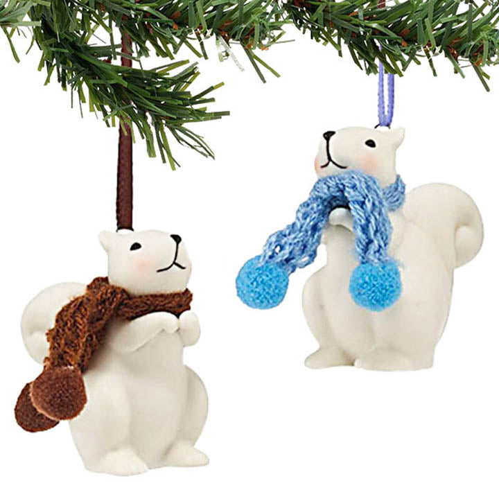 Two department 56 squirrel with scarves ornaments hanging on a Christmas tree.