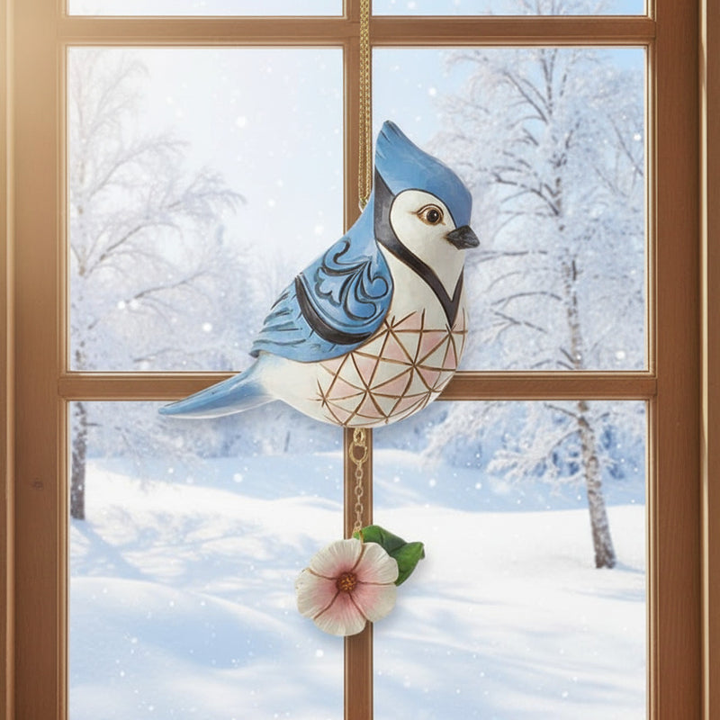 Jim Shore  blue jay bird ornament hanging in window with winter scene in background