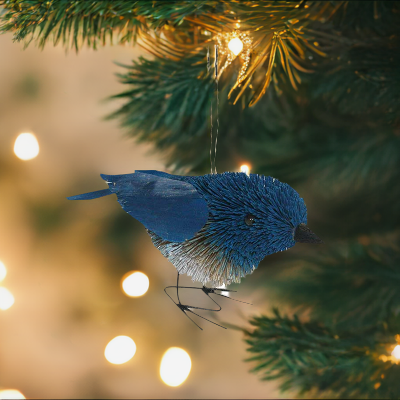 bottle brush bluebird ornament hanging from christmas tree branch with lights in background