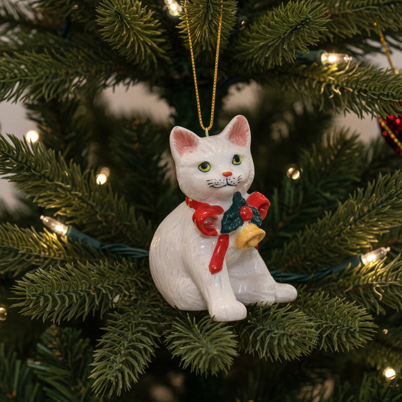 Little Criterz Northern Rose white kitten ornament with a red bow and bell hanging in Christmas tree