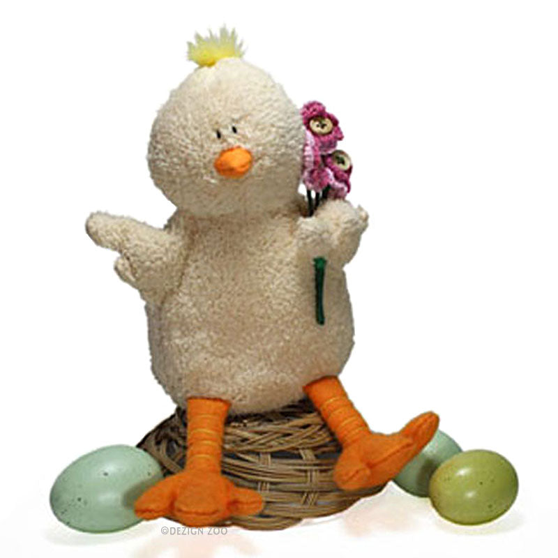 Plush toy duck with a flower in its wing sitting on a inverted nest with eggs on a white background