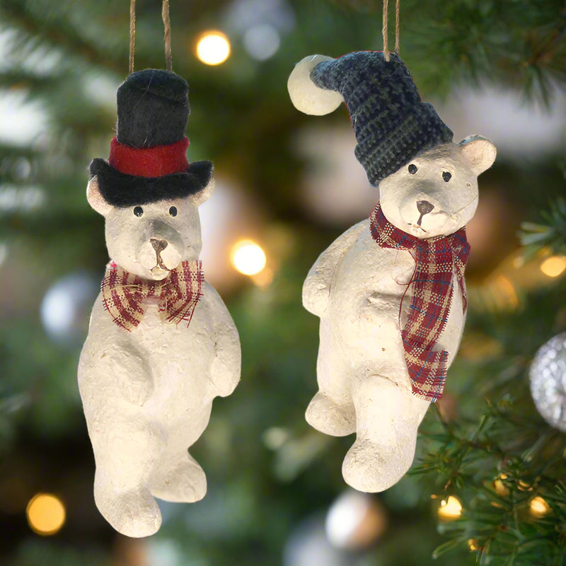 2 paper pulp polar bear ornaments in hats and scarves with christmas tree and lights in background