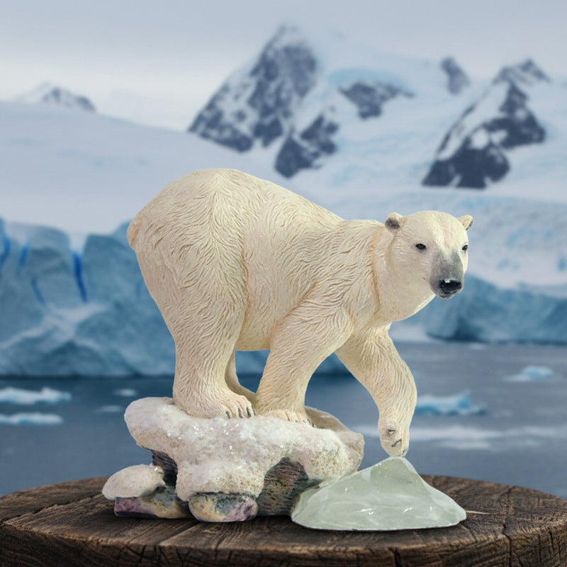 Polar bear figurine standing on snow and ice with a ocean glacial mountains in background