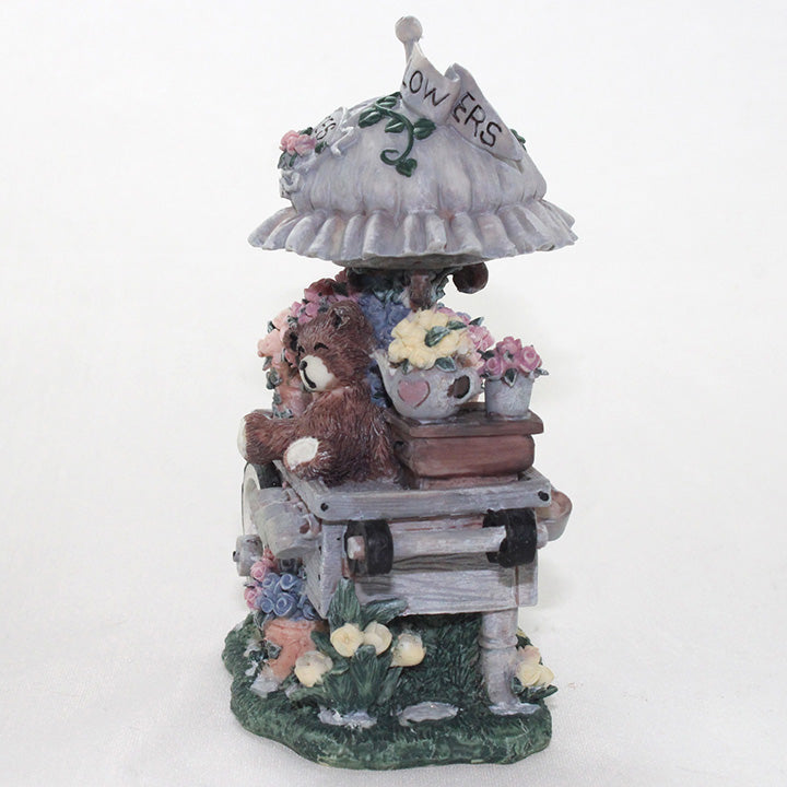 End view of decorative figurine of a bear with flowers and a flower stand on a white background