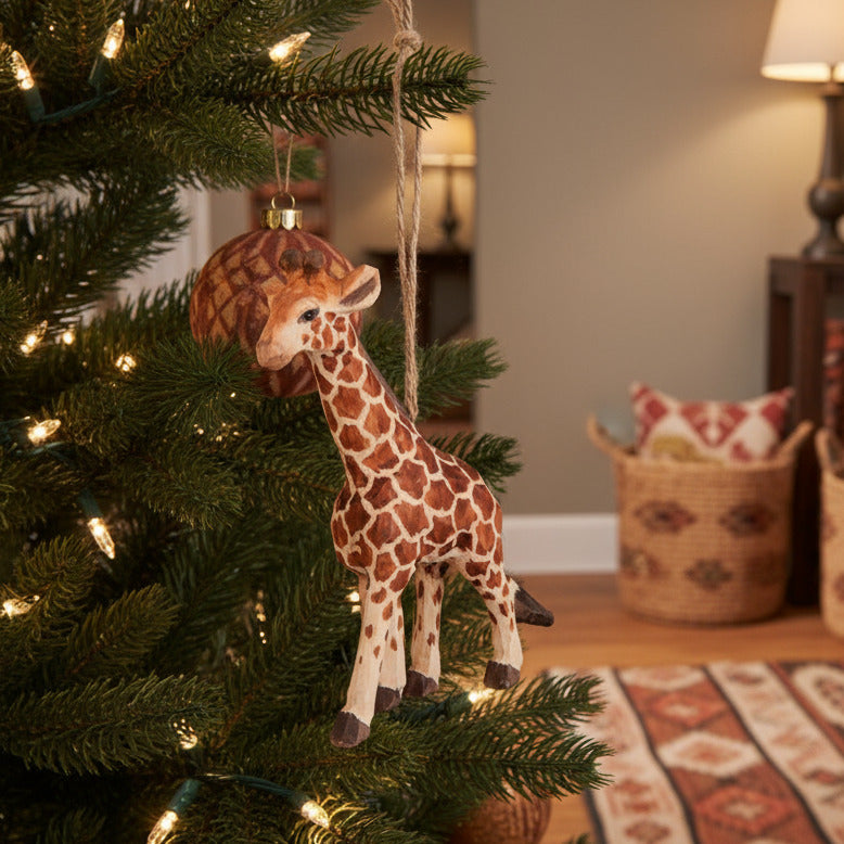 hand carved and painted giraffe ornament hanging in Christmas tree with African style decor in background