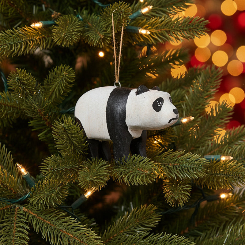 carved wood  panda ornament hanging in lit christmas tree