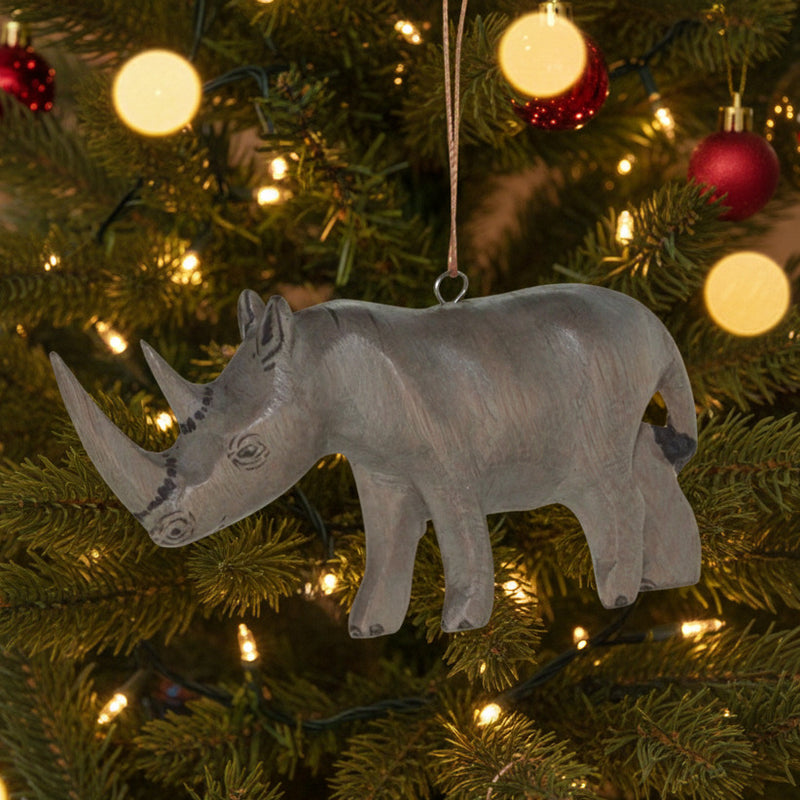 Decorative carved wood rhinoceros ornament hanging in lighted Christmas tree