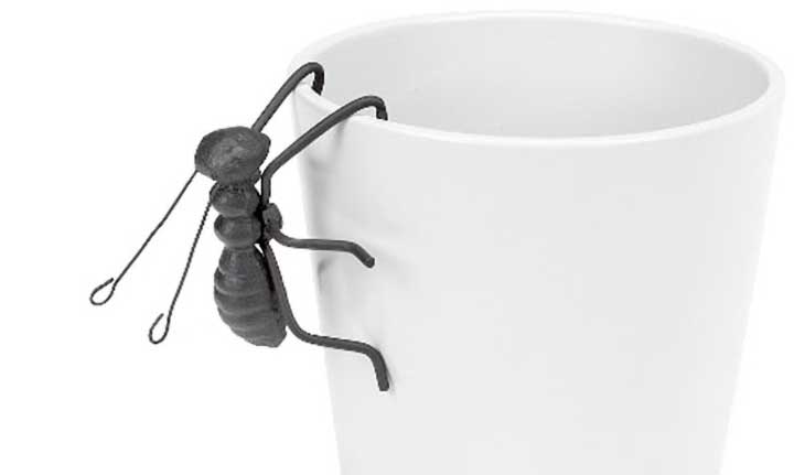 cast iron ant figurine pot hanger handing from side of planter