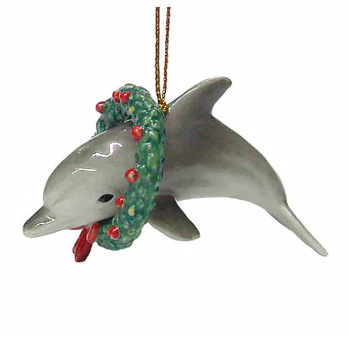 porcelain dolphin wearing a christmas wreath with red bow and decorations ornament hanging from gold colored cord
