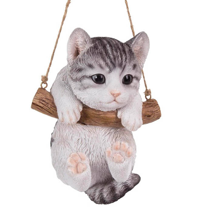 front view of gray tabby kitten with front paws over a brown branch suspended by jute rope hanger figurine