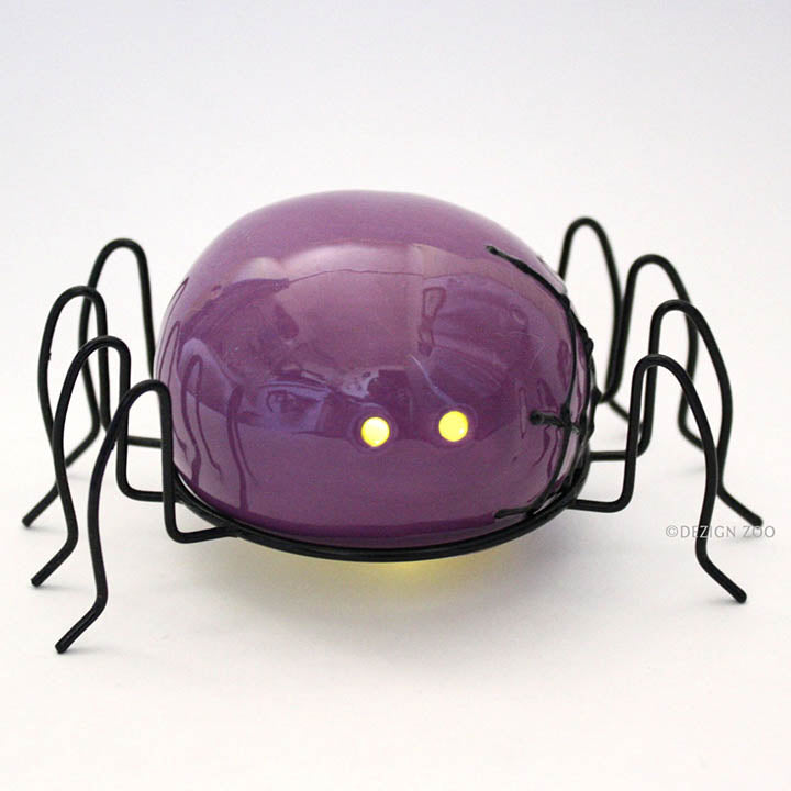 small purple spider halloween figurine with black metal legs front view showing yellow LED eyes