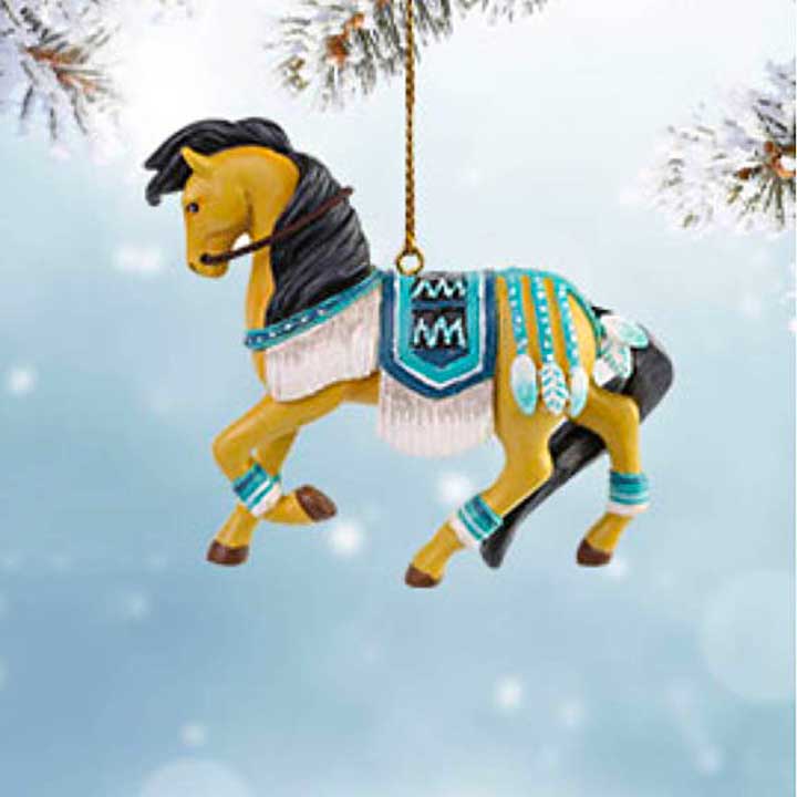 trail of painted ponies turquoise princess ornament - shown hanging from tree branch from gold cord in vinette with blue and snowflake background